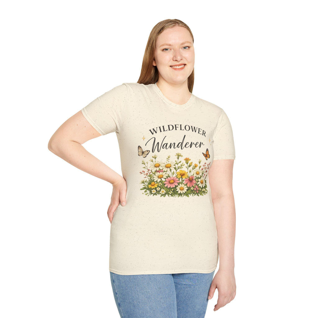 A smiling woman with long blonde hair wears a cream t-shirt with a graphic of colorful wildflowers and butterflies, with the text "WILDFLOWER Wanderer" above.