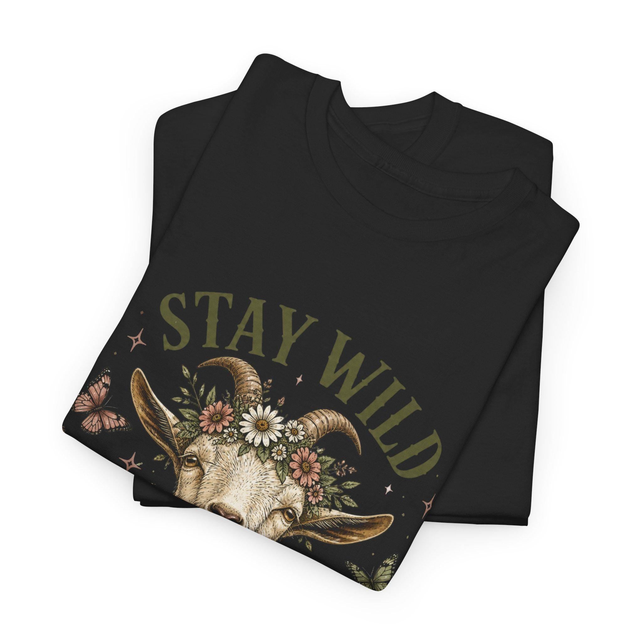 Two folded black t-shirts, with the top one displaying the upper half of a goat wearing a floral crown and the text "Stay Wild."