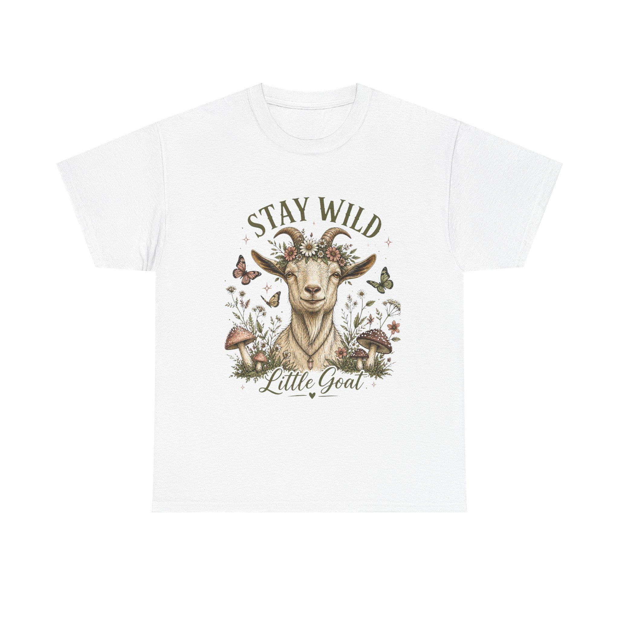 A white t-shirt with a graphic of a goat wearing a floral crown, surrounded by mushrooms and butterflies, with the text "Stay Wild Little Goat."