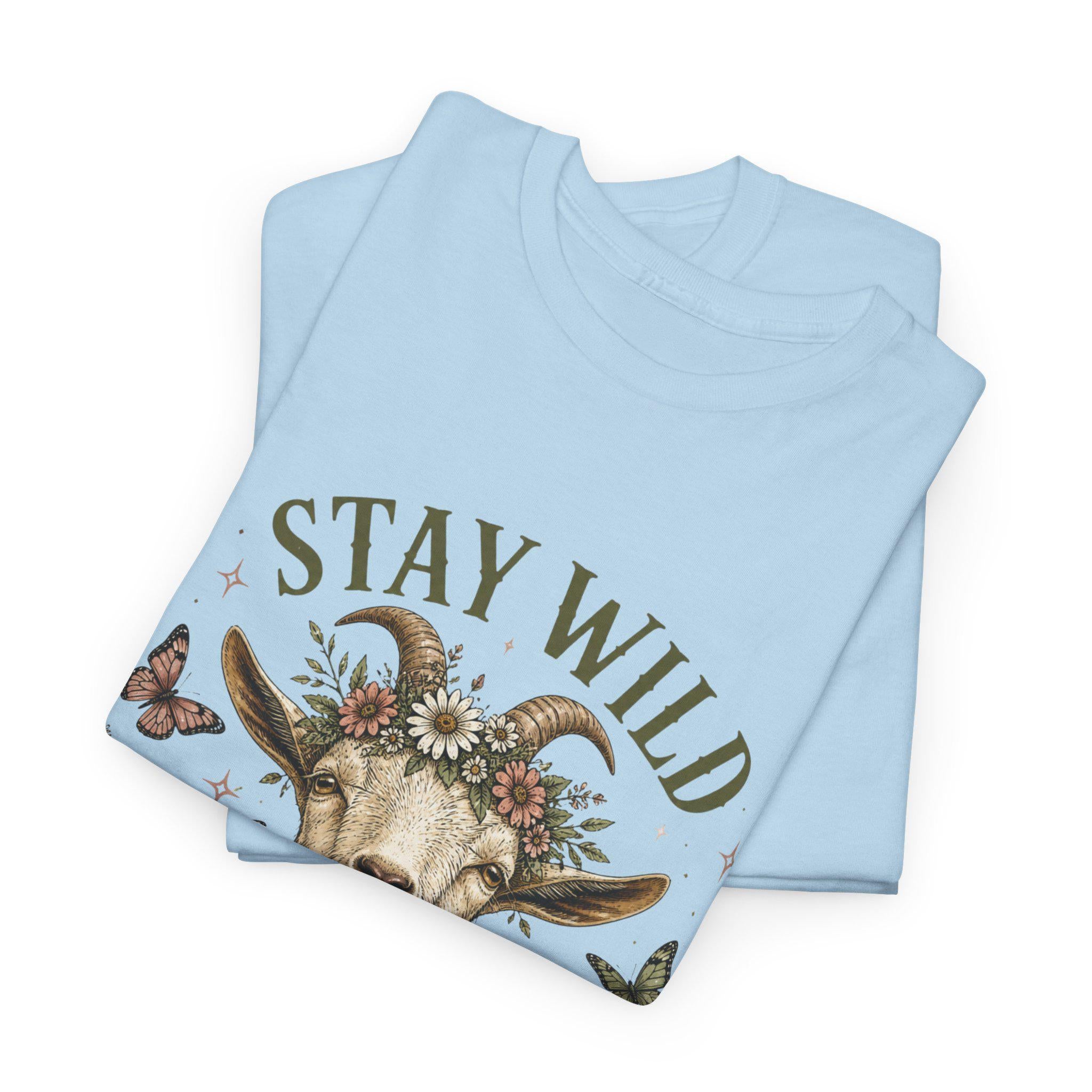A folded light blue t-shirt with a graphic of a goat's head wearing a floral crown, surrounded by the words "STAY WILD" and butterflies.