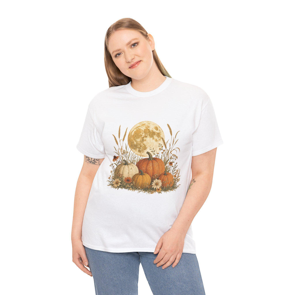 A woman with blonde hair wearing a white t-shirt with a graphic of a full moon behind a patch of pumpkins, tall grass, and flowers.