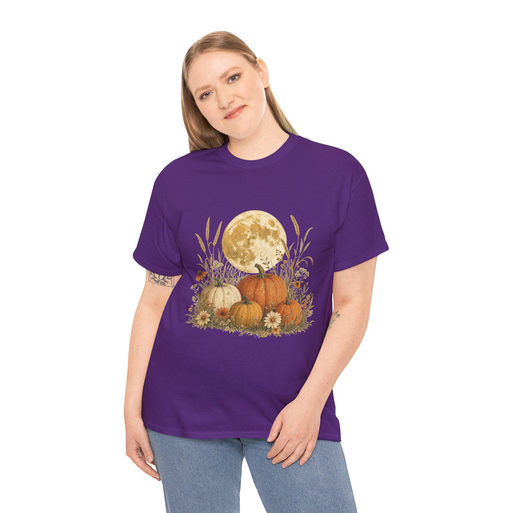 A woman models a purple t-shirt featuring a graphic of a large full moon behind a cluster of pumpkins, tall grasses, and small flowers.