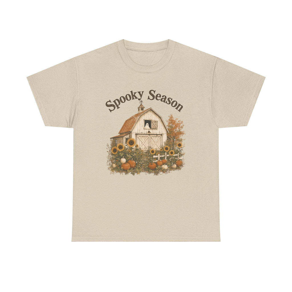 A light tan t-shirt with a graphic of a barn, sunflowers, pumpkins, and a ghost in a window, with "Spooky Season" text.
