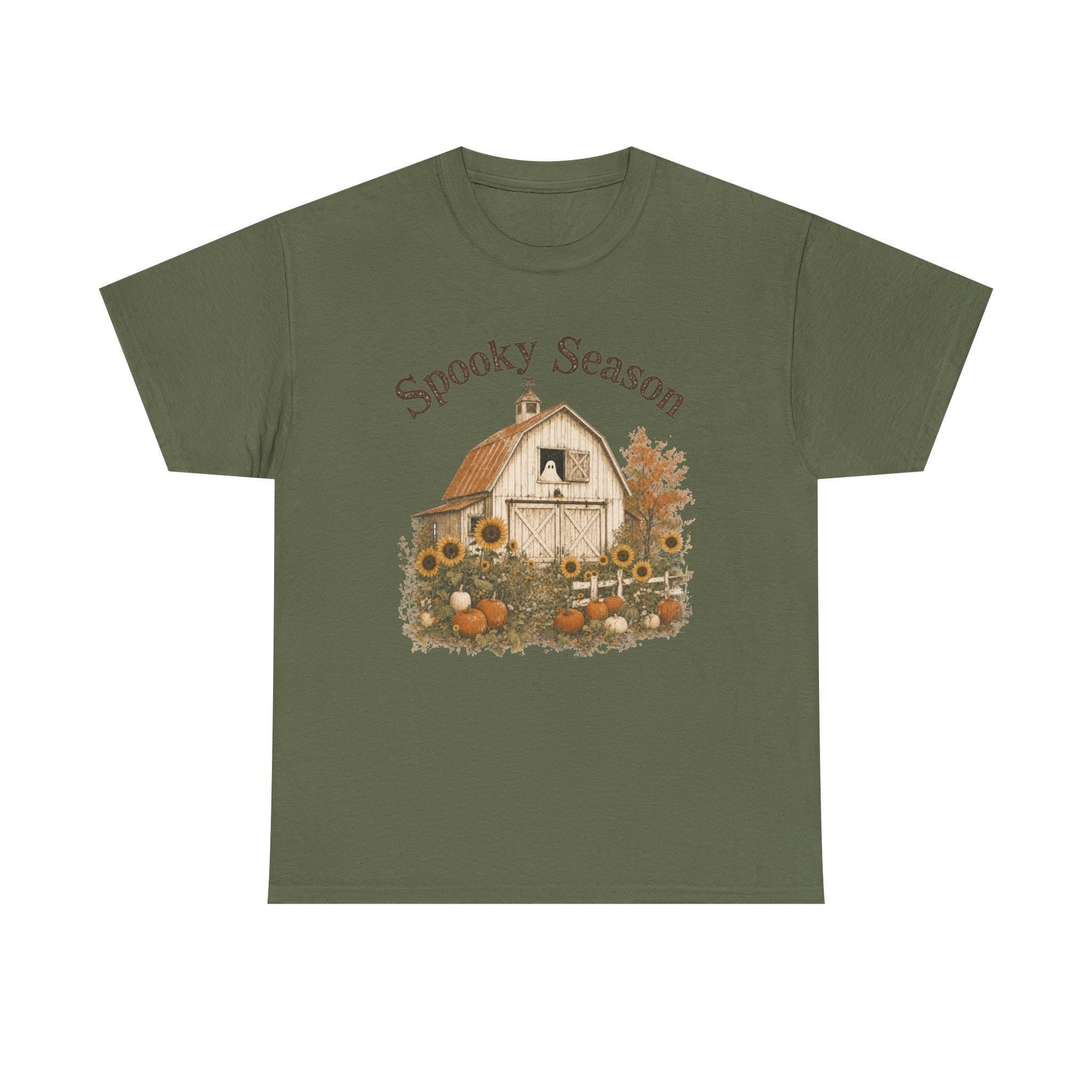 An army green t-shirt with a graphic of a barn, sunflowers, pumpkins, and a ghost in a window, with "Spooky Season" text.