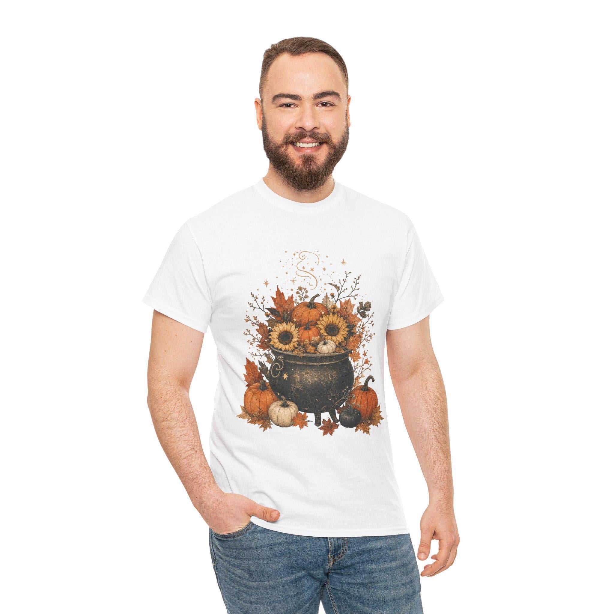A smiling man with a beard wears a white short-sleeved t-shirt with a fall-themed graphic of a black cauldron filled with sunflowers, pumpkins, and autumn leaves.
