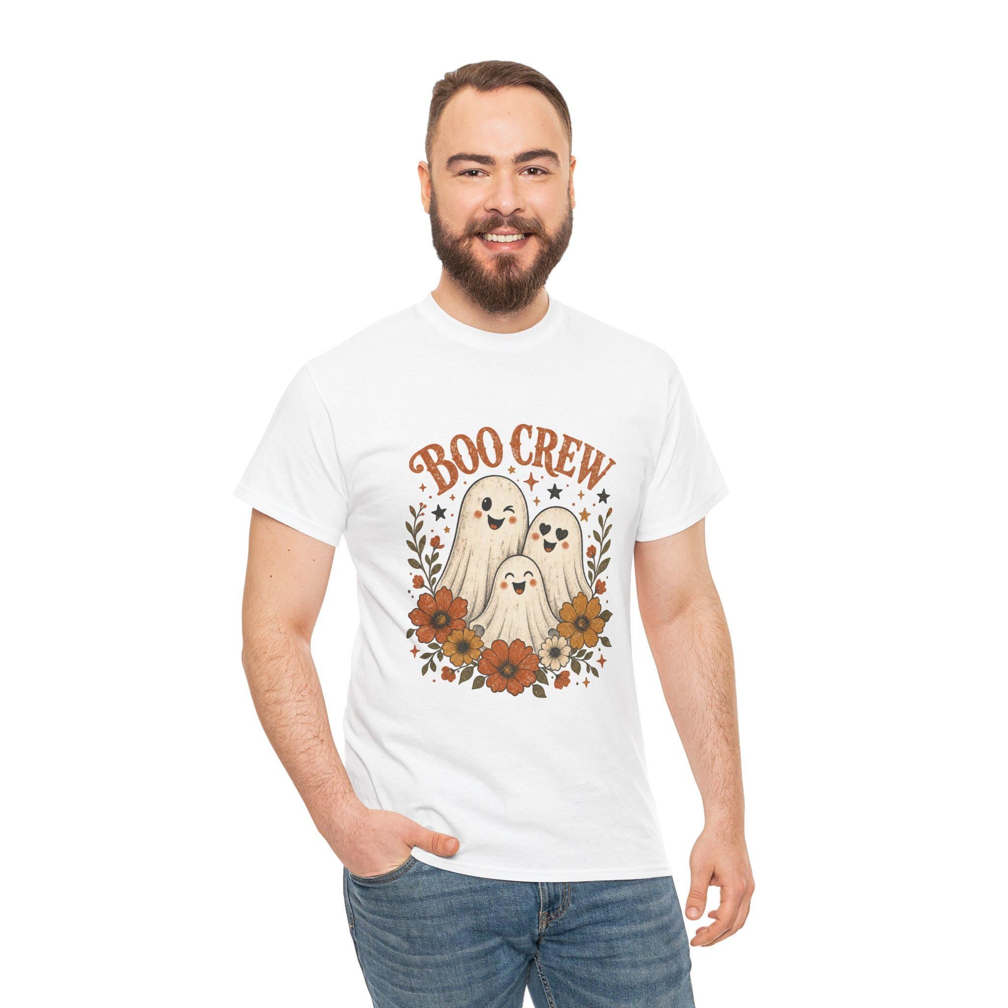 A man with a beard and short brown hair smiles, wearing a white t-shirt with "BOO CREW" and three smiling ghosts surrounded by orange and brown flowers.