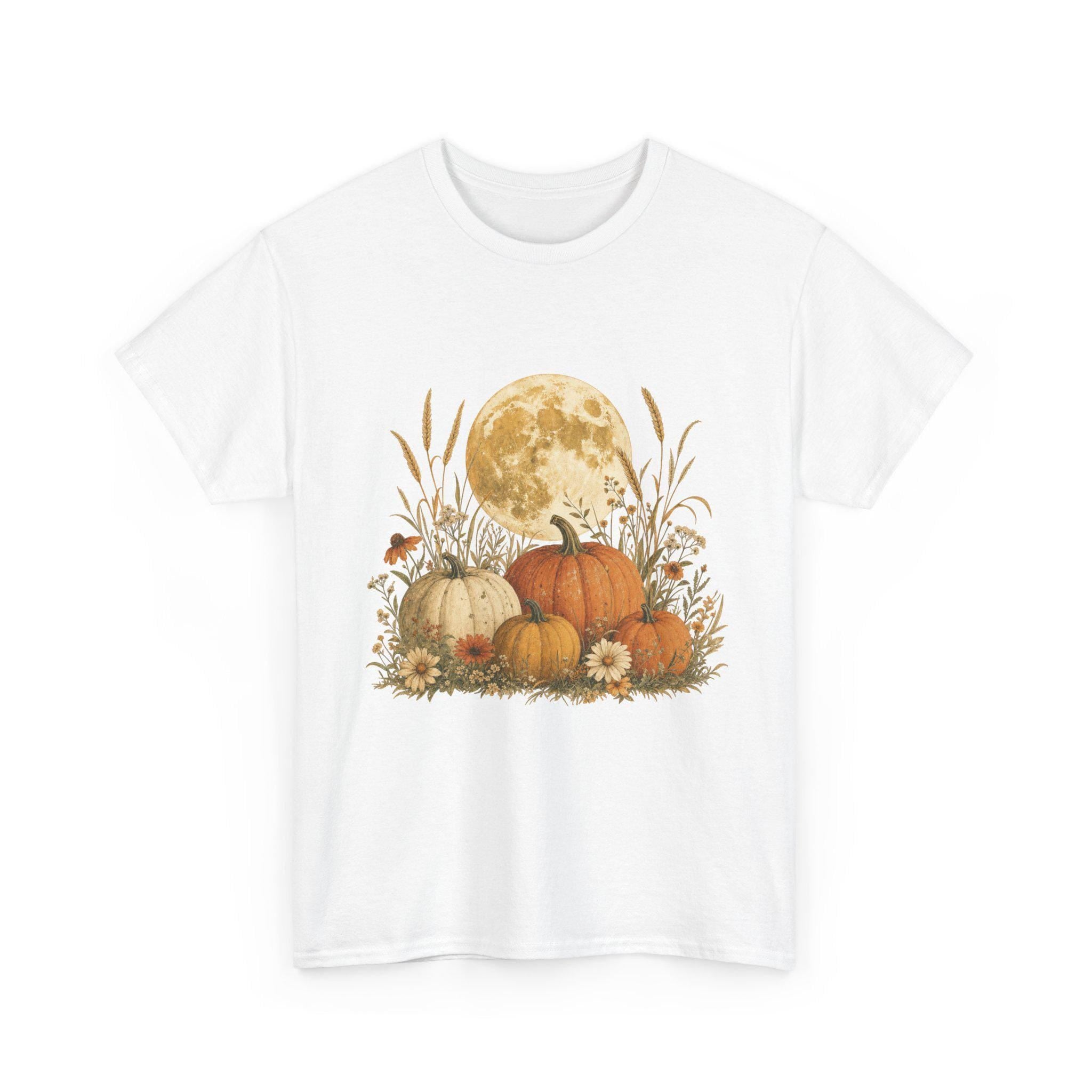 A white t-shirt displays a graphic of a large full moon behind a cluster of pumpkins, tall grasses, and small flowers.