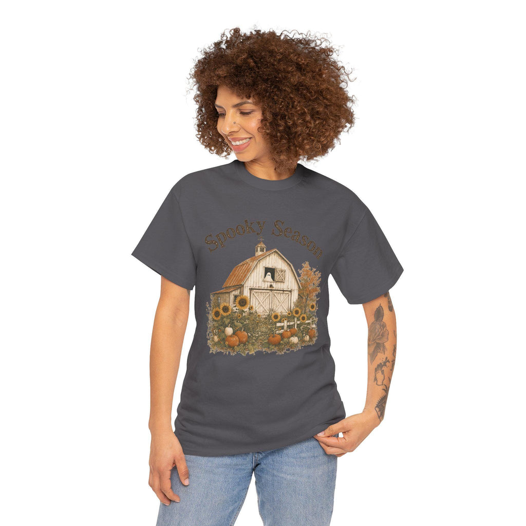A woman wearing a dark gray t-shirt with a graphic of a white barn, sunflowers, and pumpkins, with "Spooky Season" text above.
