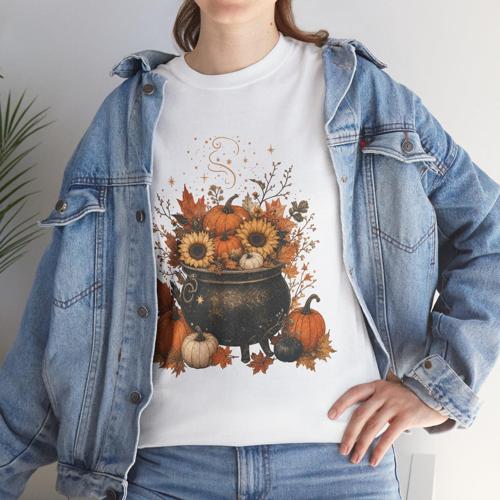 A woman in a denim jacket wears a white t-shirt with a graphic of a black cauldron filled with pumpkins, sunflowers, and autumn leaves.